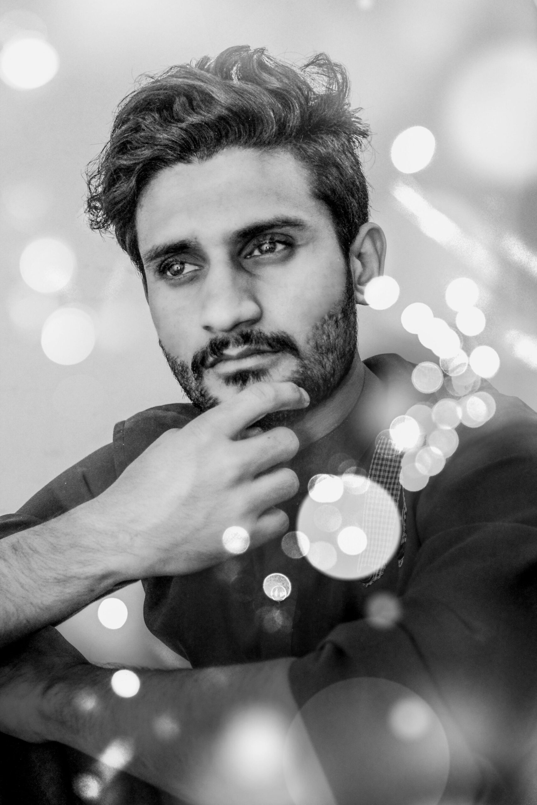 Elegant portrait of a young man in bokeh effect, emphasizing thoughtfulness and style.